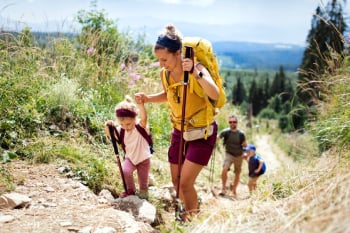 A husband and wife hiking with two young children happily talk about their decision to buy international health insurance.