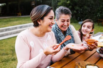 two Greek women and a young girl preparing food outside having secured health insurance for Greek expats