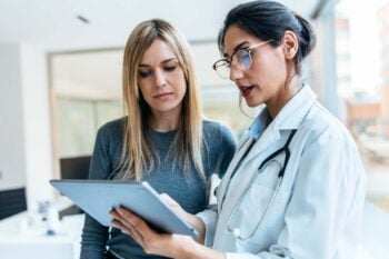 a female patient talking to a doctor and looking at a clipboard