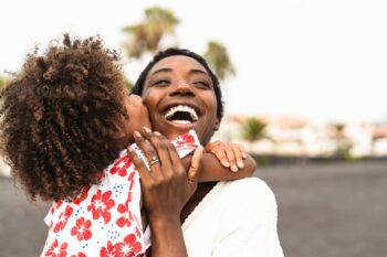 a happy Bahamian woman smiling and hugging her child, safe in the knowledge that she has insurance for Bahamian citizens