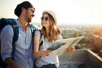 A young couple with backpacks smiling while holding a map, symbolizing the peace of mind that comes with single-trip travel insurance coverage