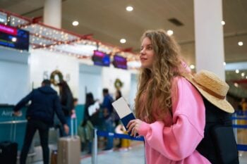 a young woman queuing at the airport, avoiding crowds by following clever holiday travel tips