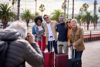 A group of travelers posing with their luggage in a sunny destination, showcasing the benefits of group travel insurance