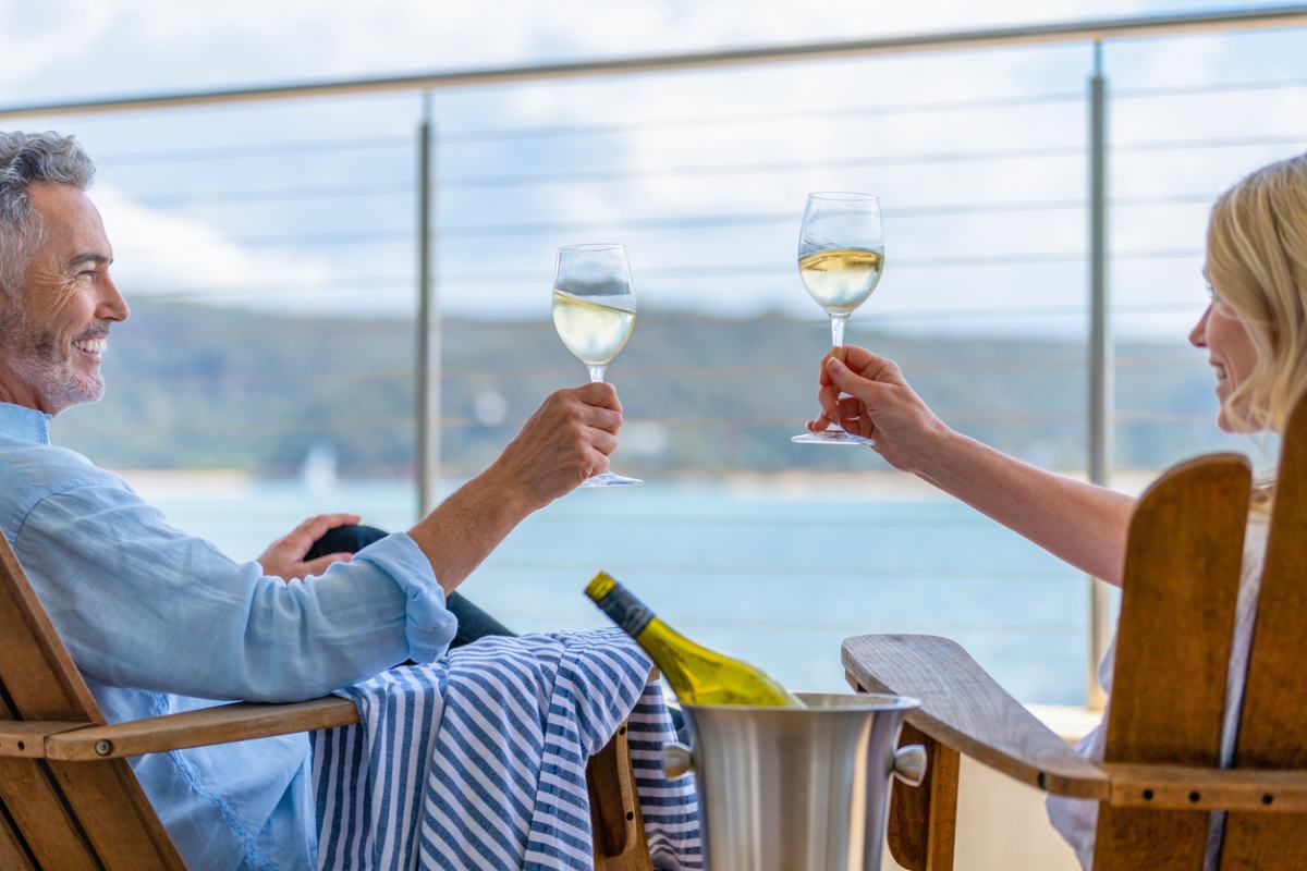 A mature couple drinking wine on the deck of a ship having researched cruise tips for relaxing onboard