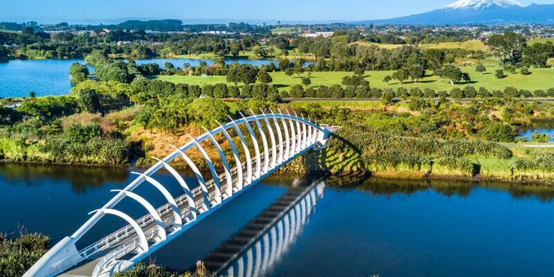 Aerial view on a beautiful bridge across a small stream with Mount Taranaki on the background, New Zealand