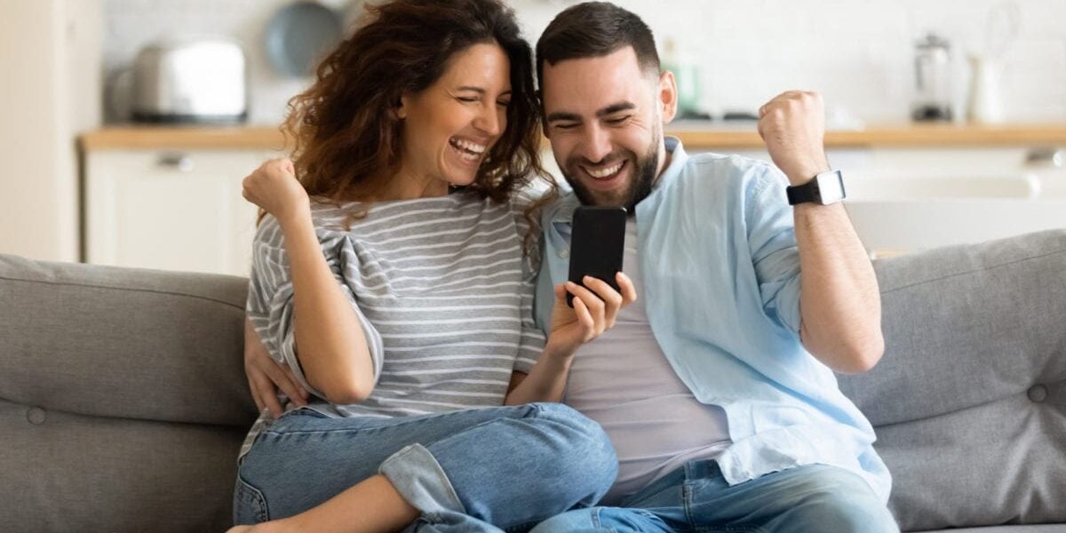 a happy couple sitting on a sofa, safe in the knowledge that they are covered by private health insurance in Canada