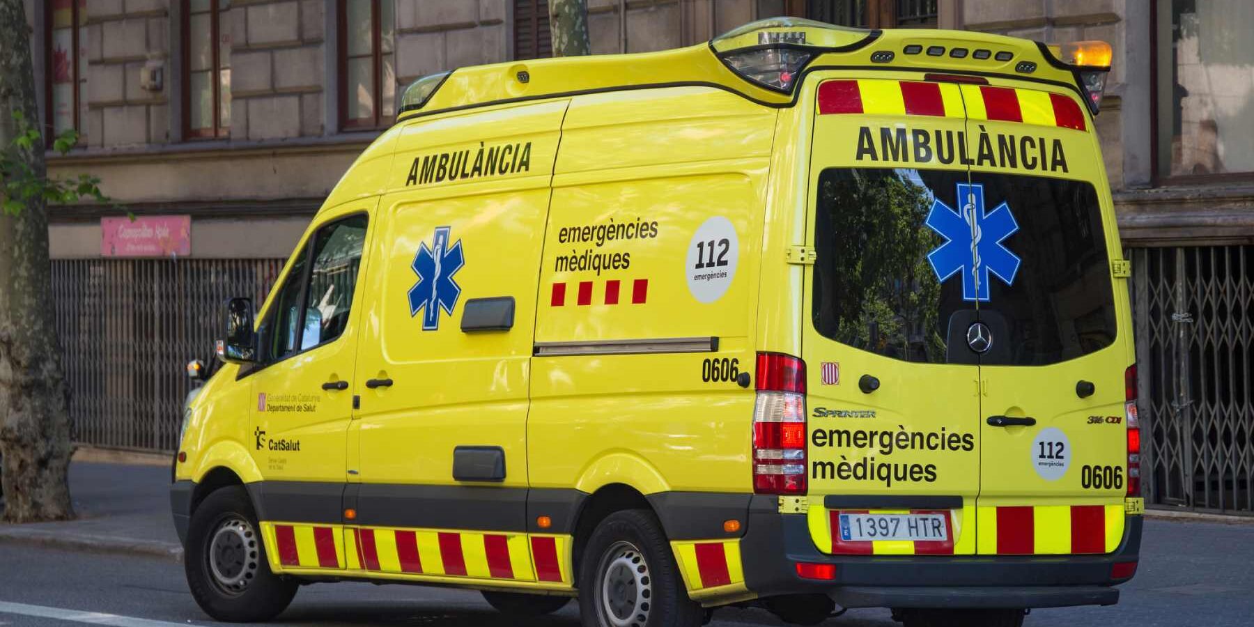 a yellow ambulance driving along a street in central Barcelona