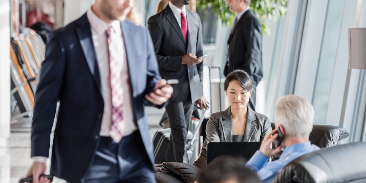 Business professionals in an airport lounge waiting for their flight, highlighting the importance of group travel insurance for corporate teams