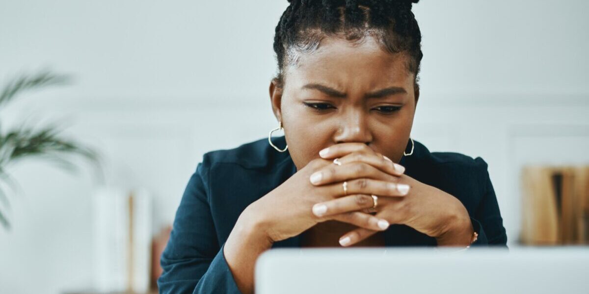 a woman frowning and looking concerned as she looks down at her laptop, reading safety tips for avoiding terrorism attacks