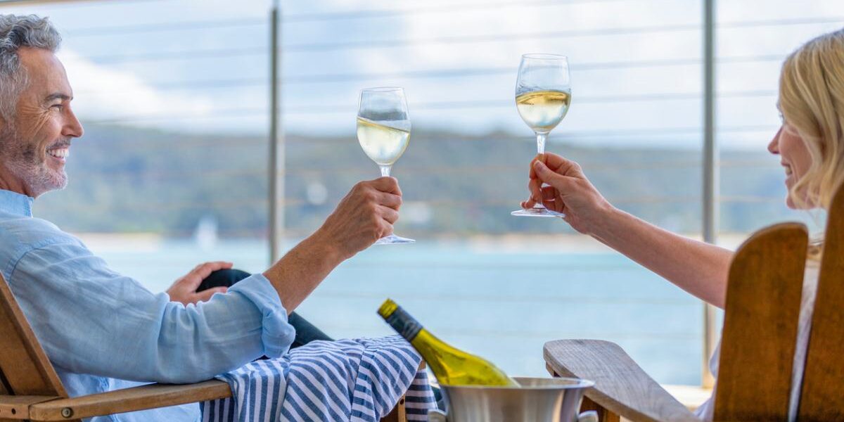 A mature couple drinking wine on the deck of a ship having researched cruise tips for