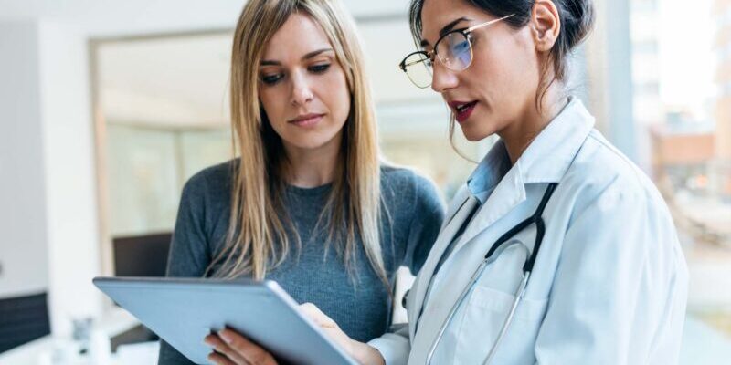 a female patient talking to a doctor and looking at a clipboard