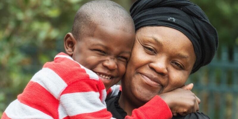 a happy Caribbean woman smiling and hugging her son