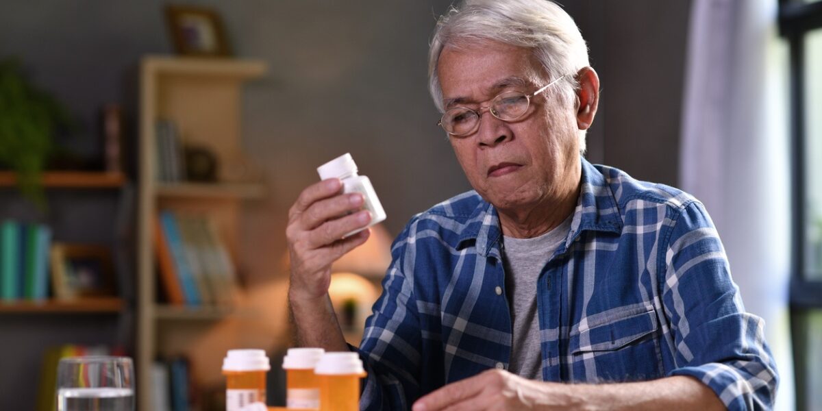 a senior man checking bottles of pescription medicine at home before taking a trip