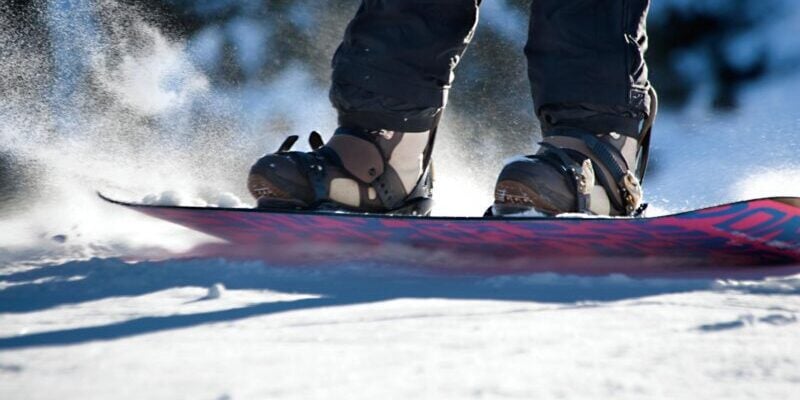 a close-up shot of a snowboard sliding down a snowy slope