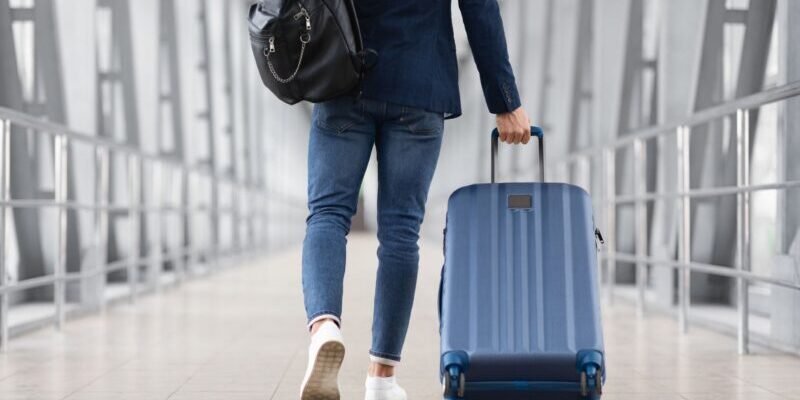 a man pulling a suitcase in an airport having read some top tips on how to buy travel insurance