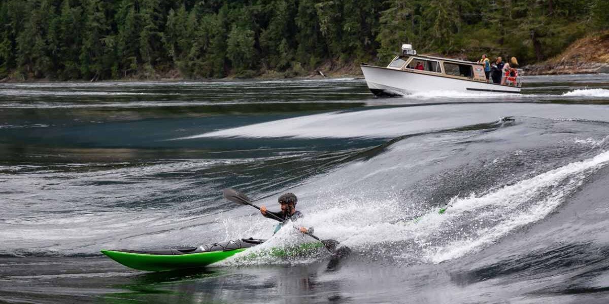 an adventurous tourist on a whitewater kayak riding a standing wave in Canada, highlighting the importance of buying travel insurance for Canada