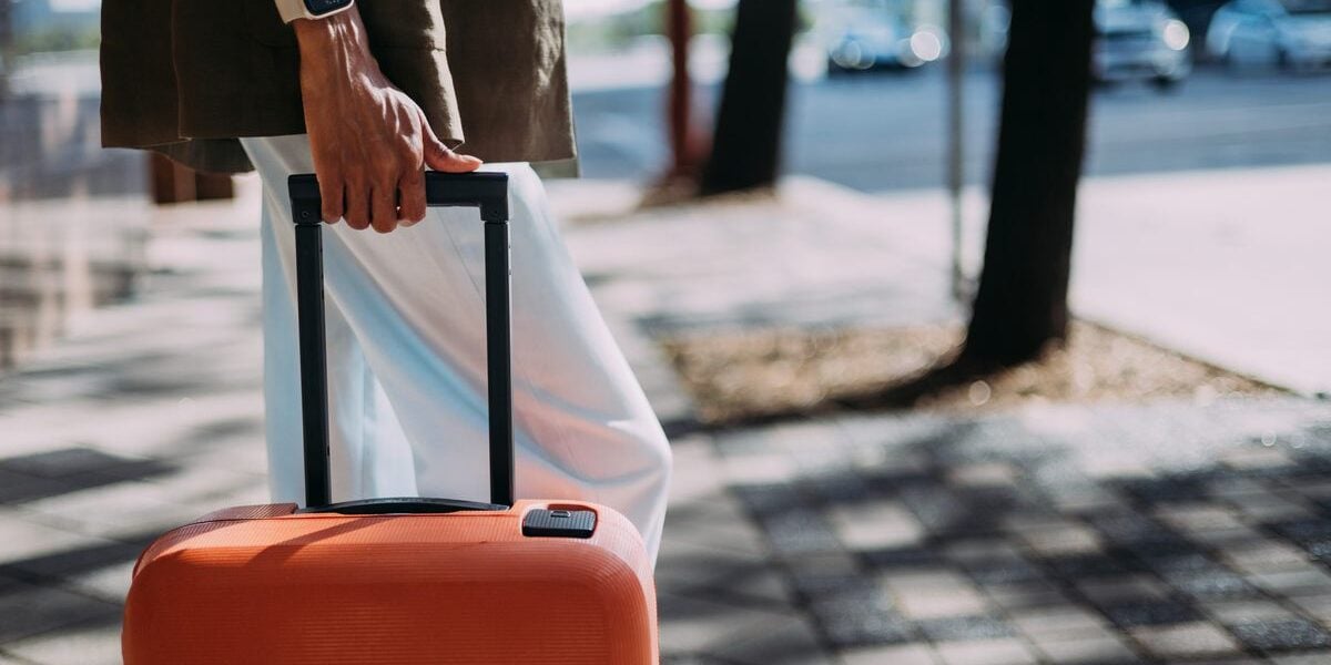 a traveler holding a suitcase on a city street, arriving a day for their cruise having read expert cruise tips